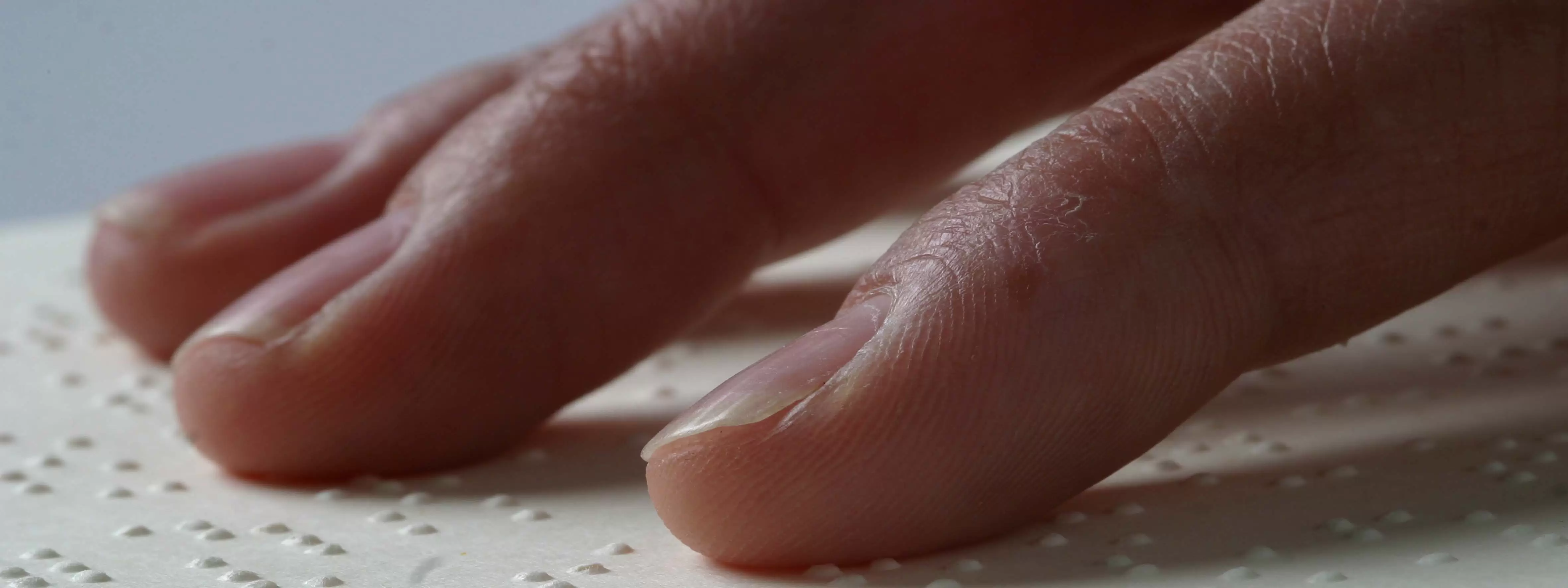 A close up of fingers reading braille text