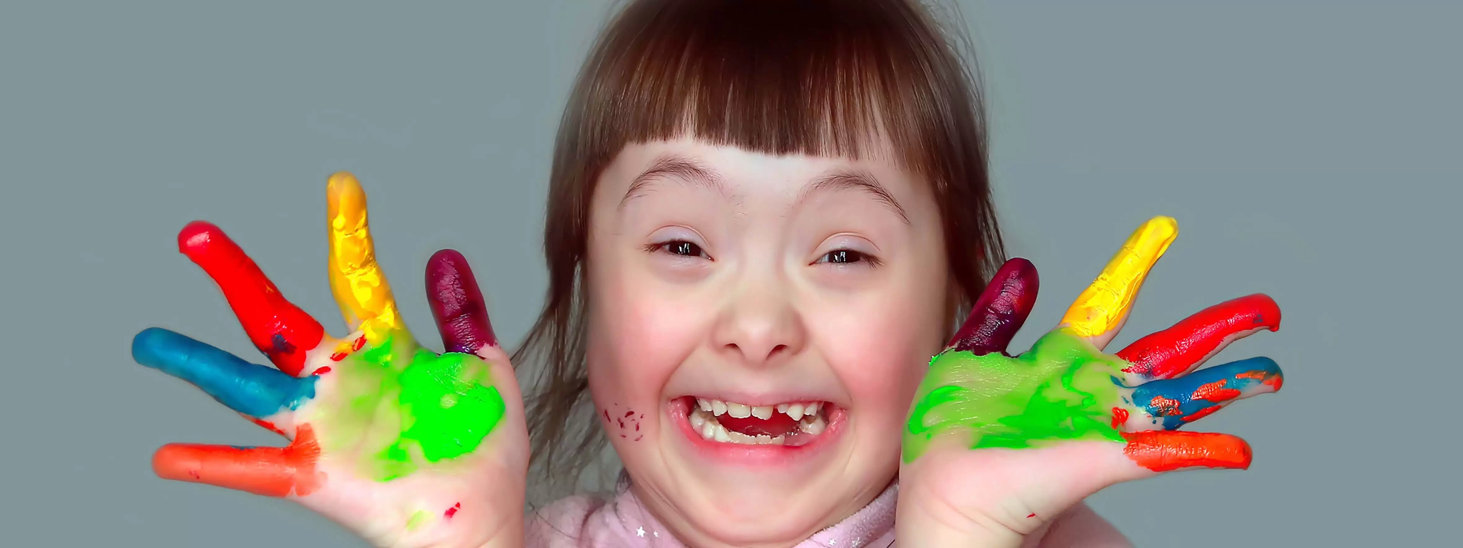 The joyful face of a little girl finger painting